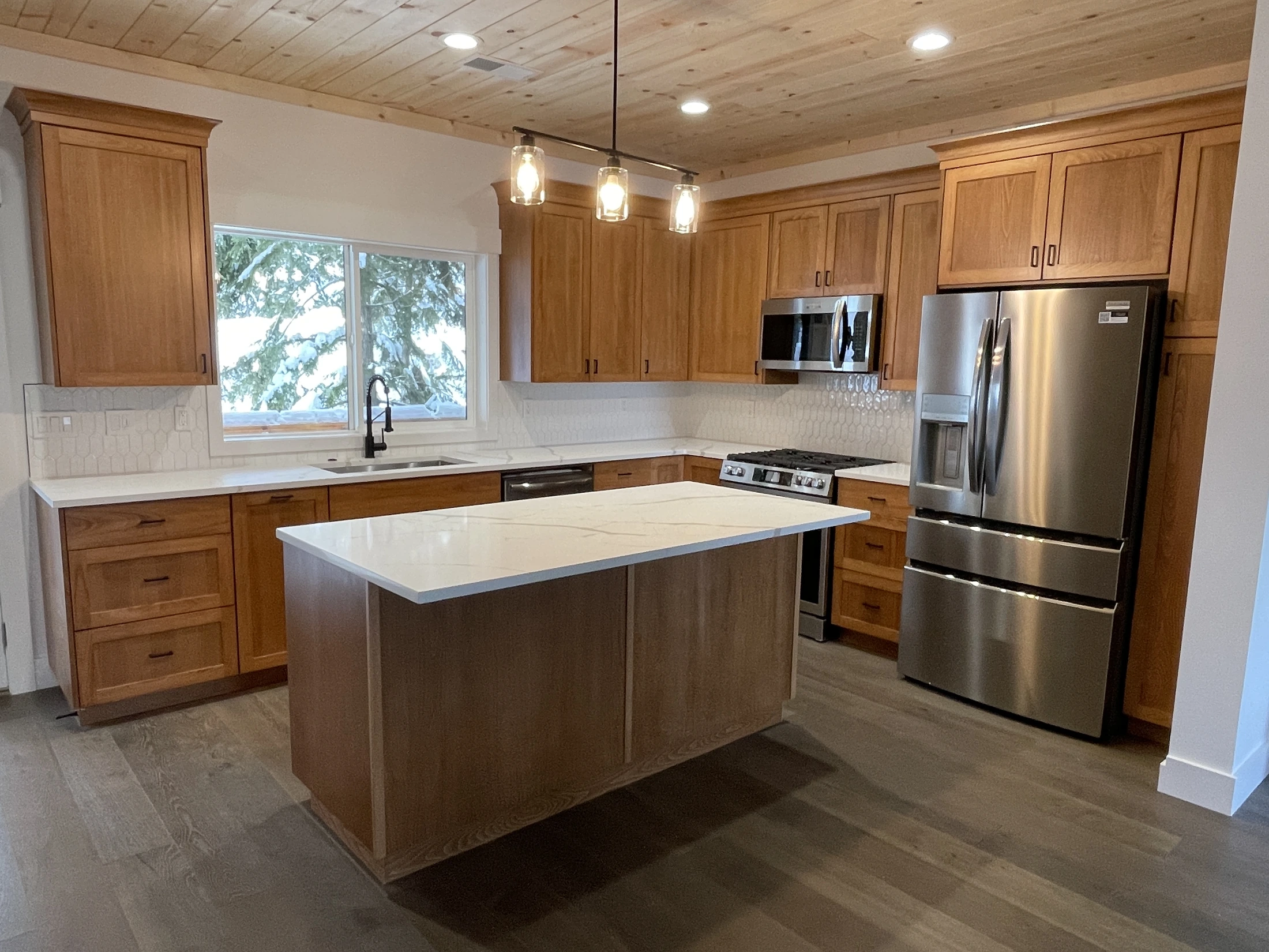 Completed oak kitchen with custom shaker cabinetry, central island, and wood ceiling