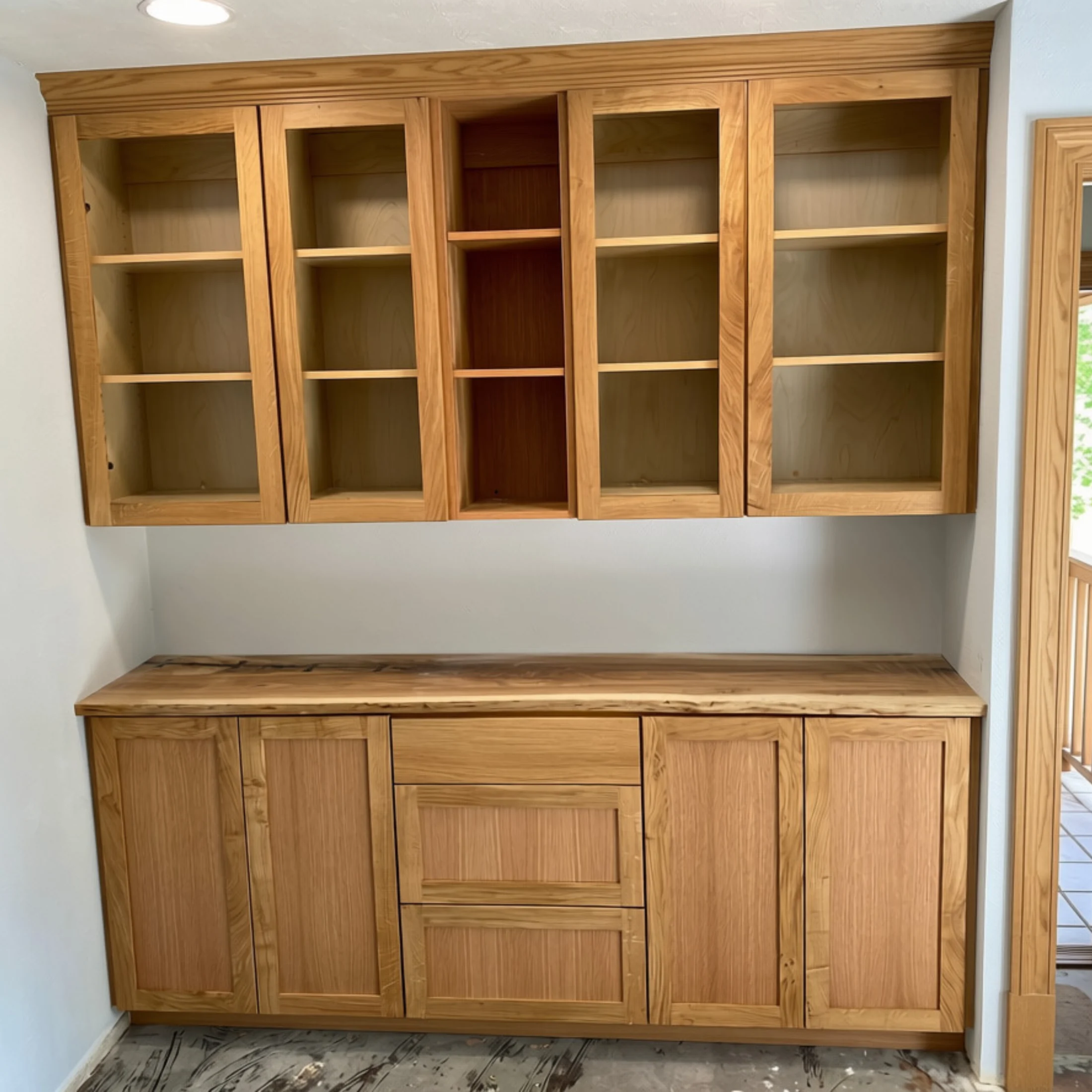 Completed oak built-in with upper molding, display cabinets, and natural-edge counter
