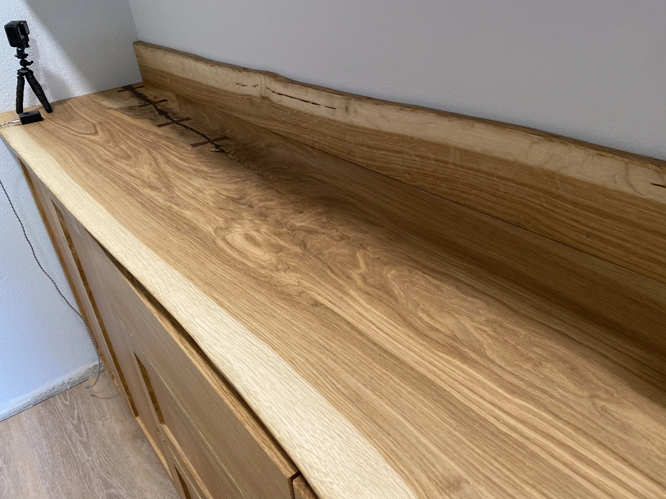 Close view of a fitted natural-edge wood cabinet top and backsplash